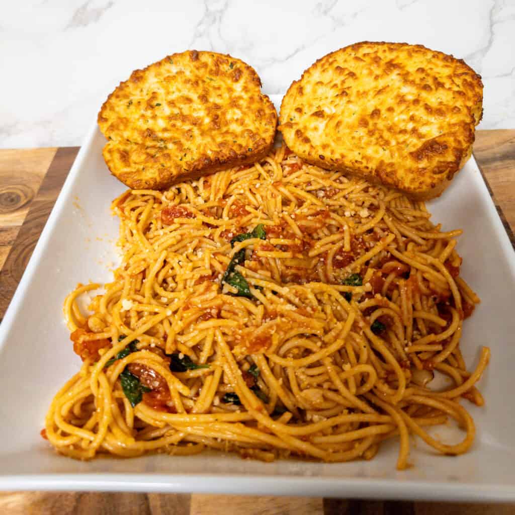 Creamy baked chicken cutlets with spaghetti in tomato sauce on plate.