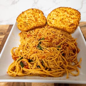 Creamy baked chicken cutlets with spaghetti in tomato sauce on plate.