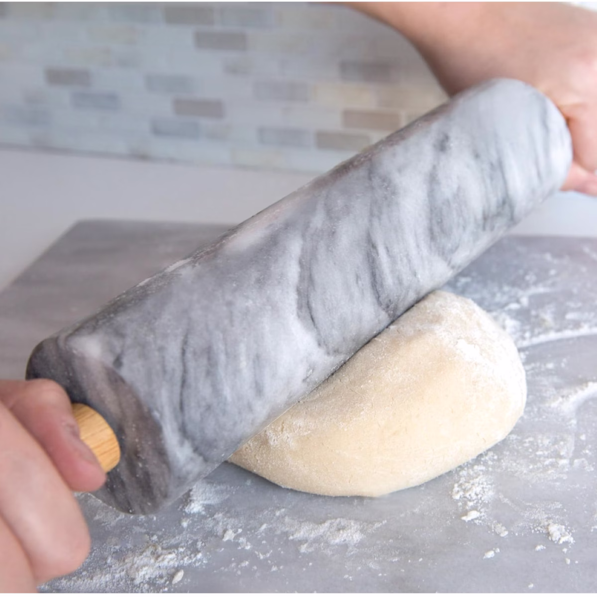 A person rolling out a dough on a rolling pin