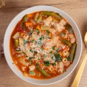 A bowl of hearty Italian minestrone soup with fresh vegetables and pasta, topped with grated cheese and herbs for authentic flavor.