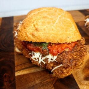 Golden Italian fried chicken parmesan sandwich with marinara sauce, shredded cheese, and crispy bread.