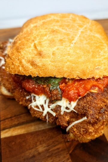 Golden Italian fried chicken parmesan sandwich with marinara sauce, shredded cheese, and crispy bread.