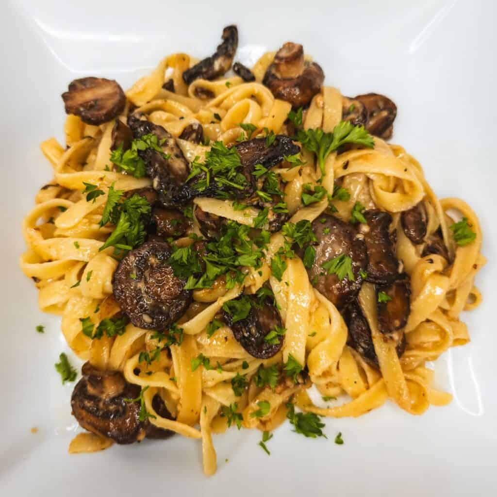 Savory mushroom and fettuccine pasta dish with fresh parsley garnish.