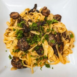 Savory mushroom and fettuccine pasta dish with fresh parsley garnish.