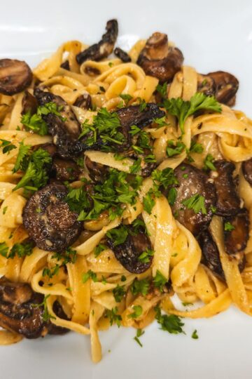 Savory mushroom and fettuccine pasta dish with fresh parsley garnish.