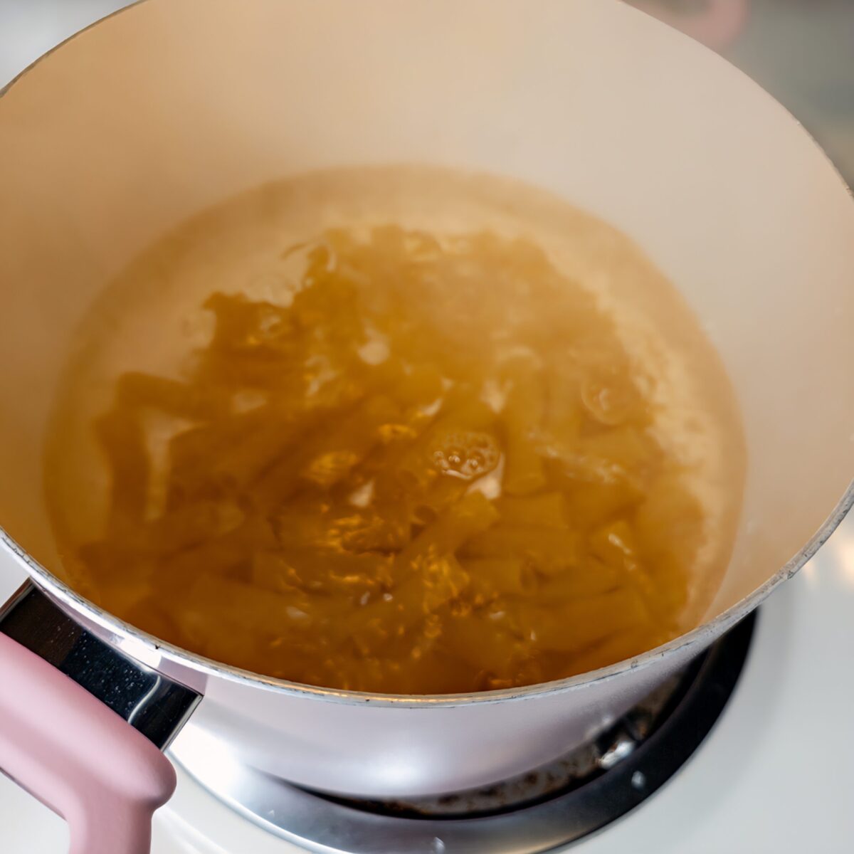 Noodles being prepared on a stove in a pot.