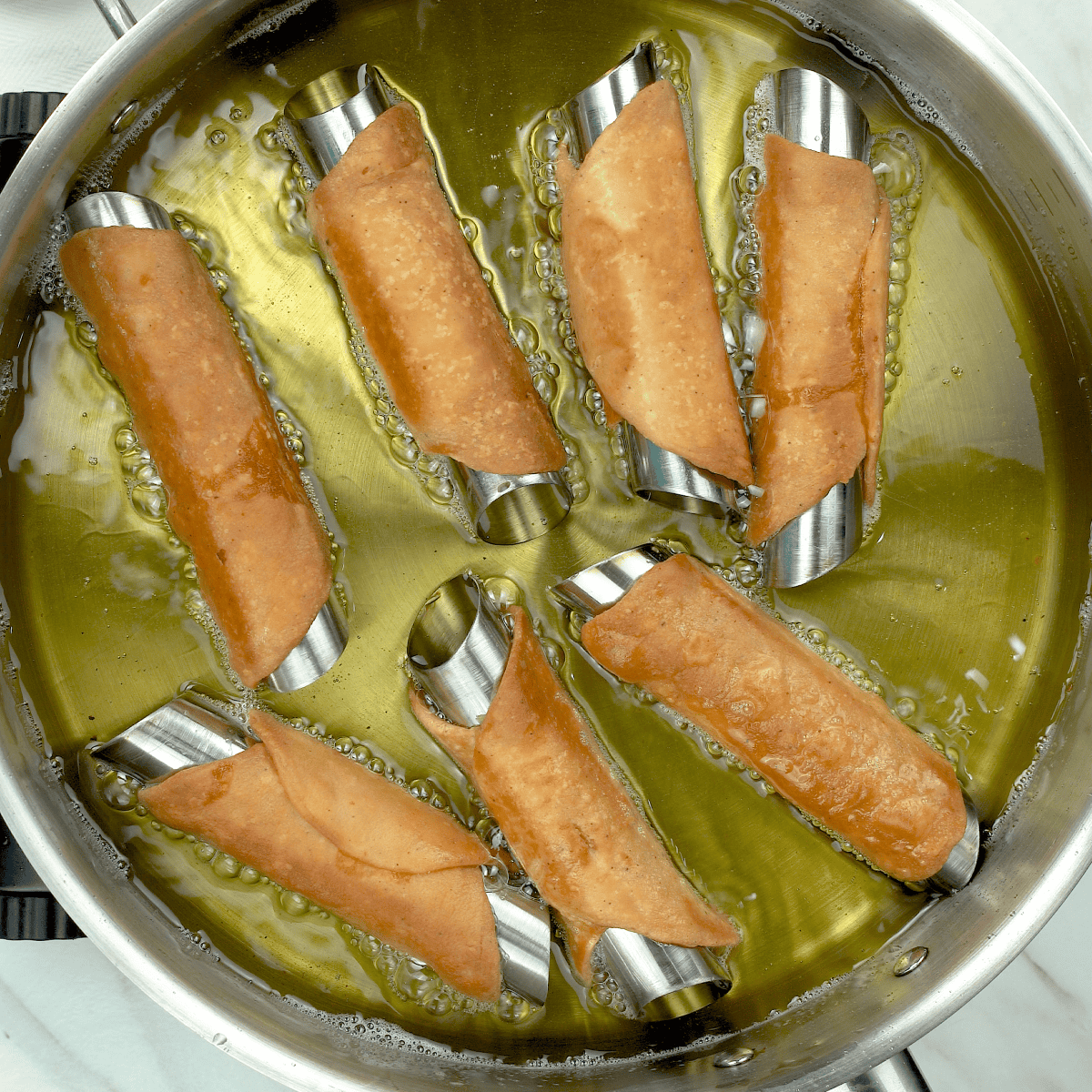 Crispy fried Italian cannoli shells in hot oil for a Classic Sicilian Cannoli