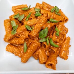 Creamy Italian Rigatoni alla Vodka pasta with basil on white plate.
