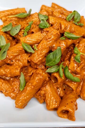 Creamy Italian Rigatoni alla Vodka pasta with basil on white plate.