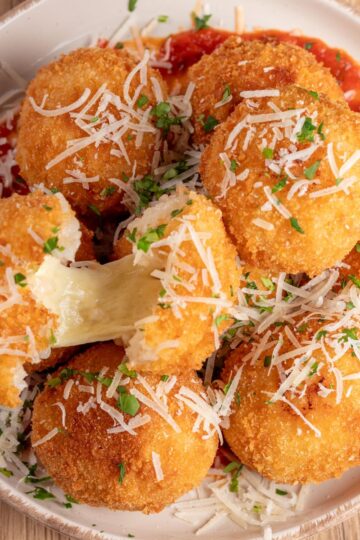 Delicious Italian arancini coated in breadcrumb and served over fresh tomato sauce.