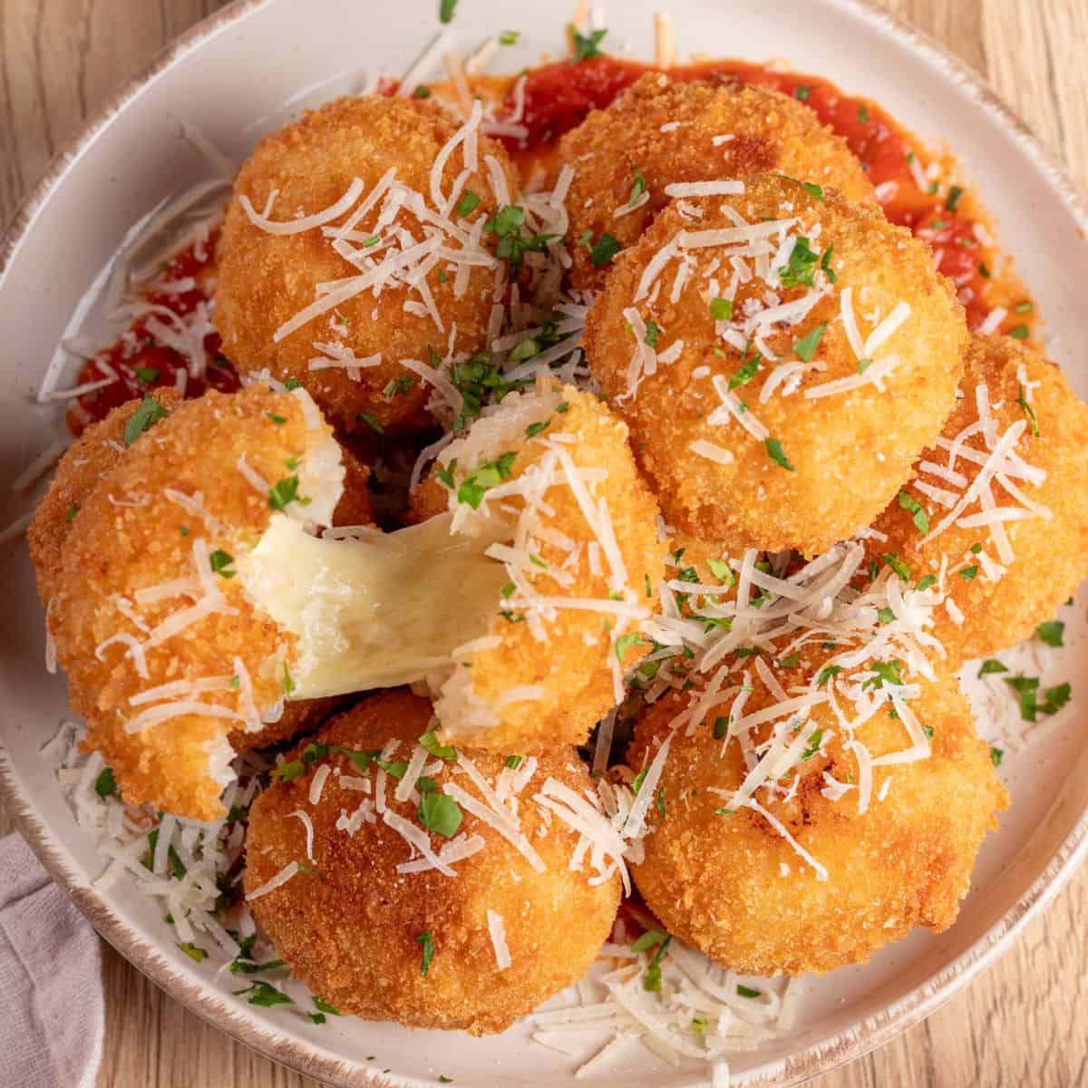 Delicious Italian arancini coated in breadcrumb and served over fresh tomato sauce.