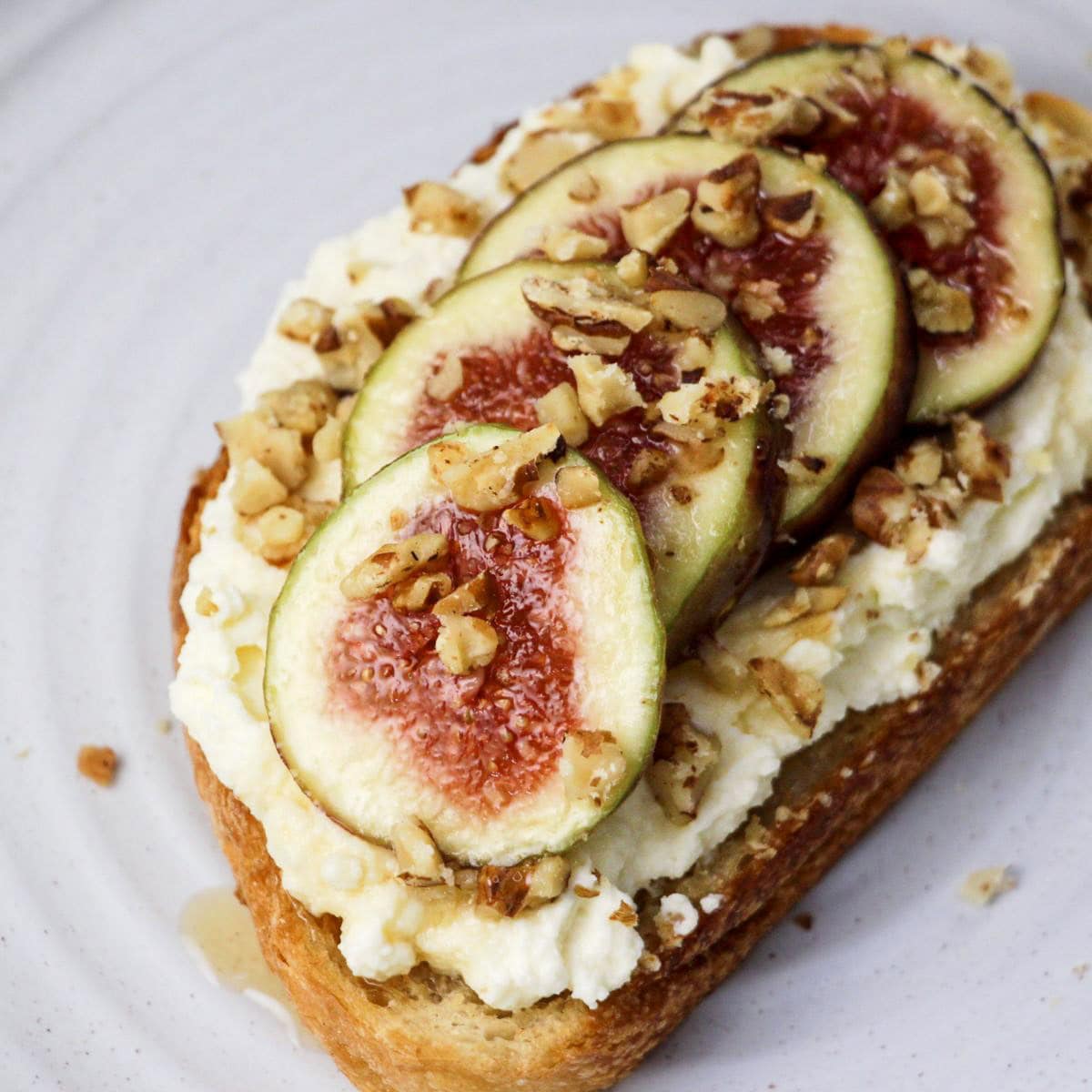 Close-up of a fig tart topped with fresh figs, cream, and chopped nuts, featured on Italian Cooking Ideas and Recipes.