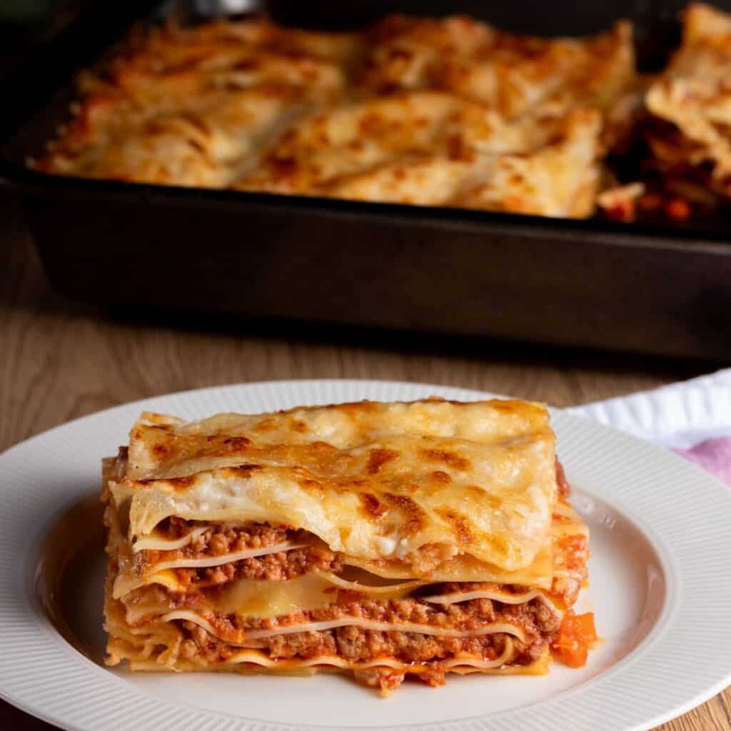 lasagna al forno served on a white plate with meat, cheese, pasta layers