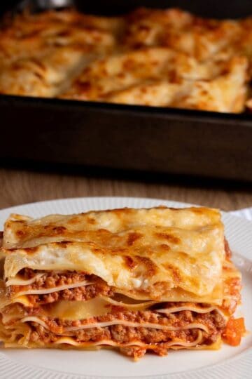 lasagna al forno served on a white plate with meat, cheese, pasta layers
