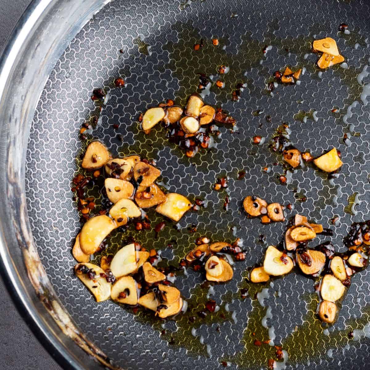 Garlic slices and red chili flakes sautéing in oil for Italian cooking recipes.