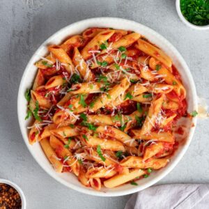 Delicious Italian pasta penne allarrabbiata served with rich tomato sauce, topped with grated cheese and fresh herbs.