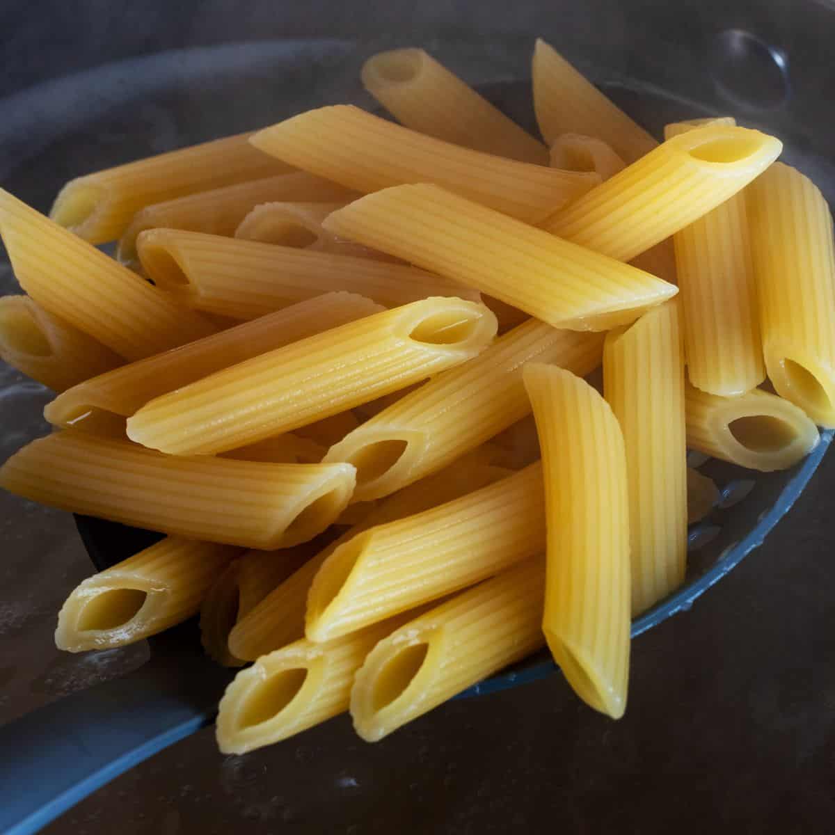 Golden uncooked penne pasta, perfect for Italian cooking recipes in a close-up shot.