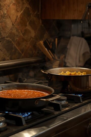 Cooking pasta and sauce on a stove in an Italian kitchen.
