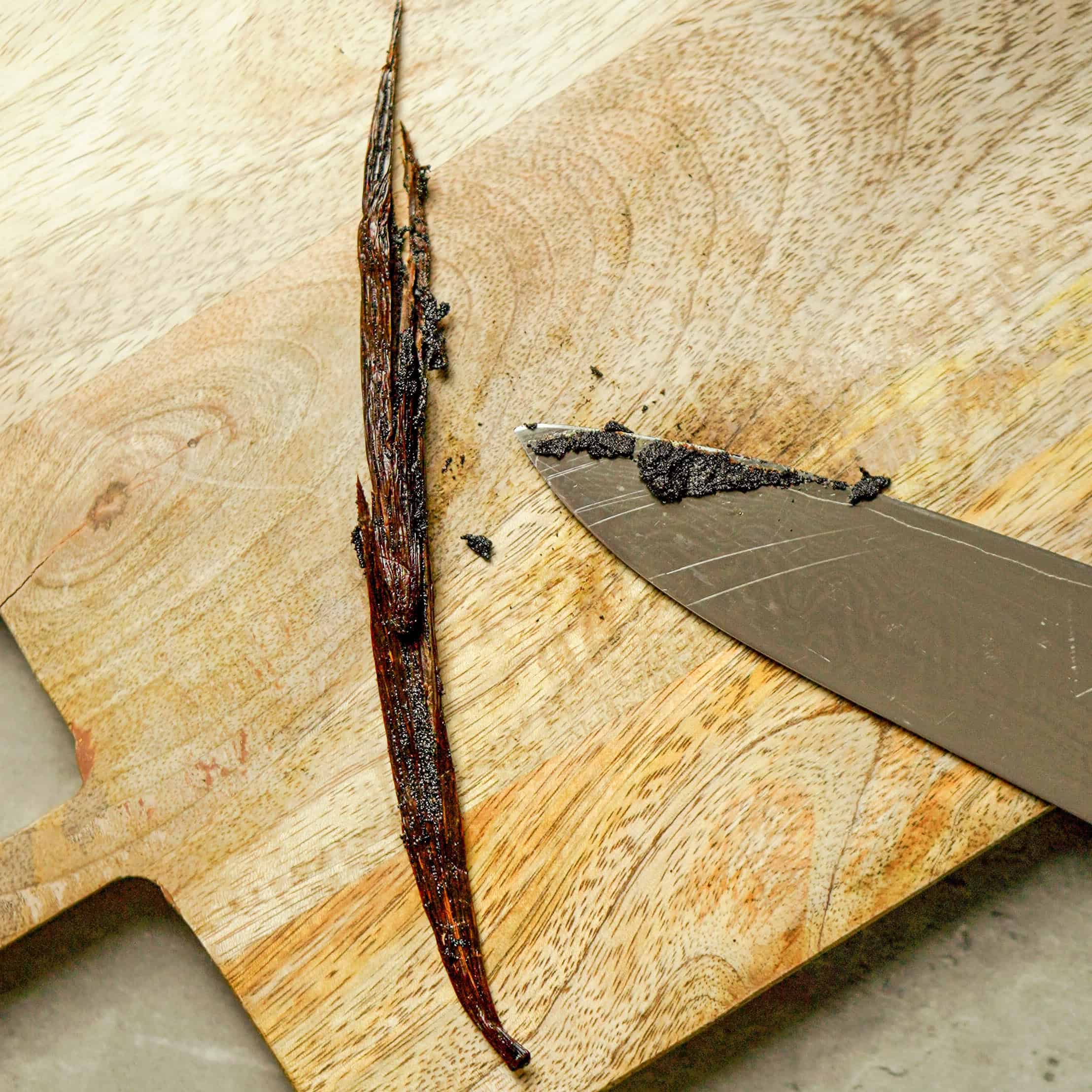 Close-up of a roasted vanilla bean on a wooden cutting board for Italian cooking recipes.