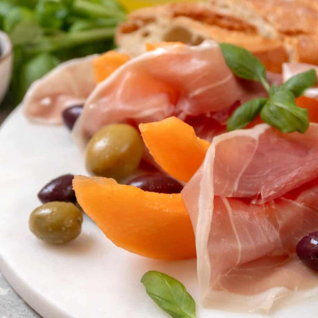 Italian antipasto platter with cured meats, olives, and fresh basil.