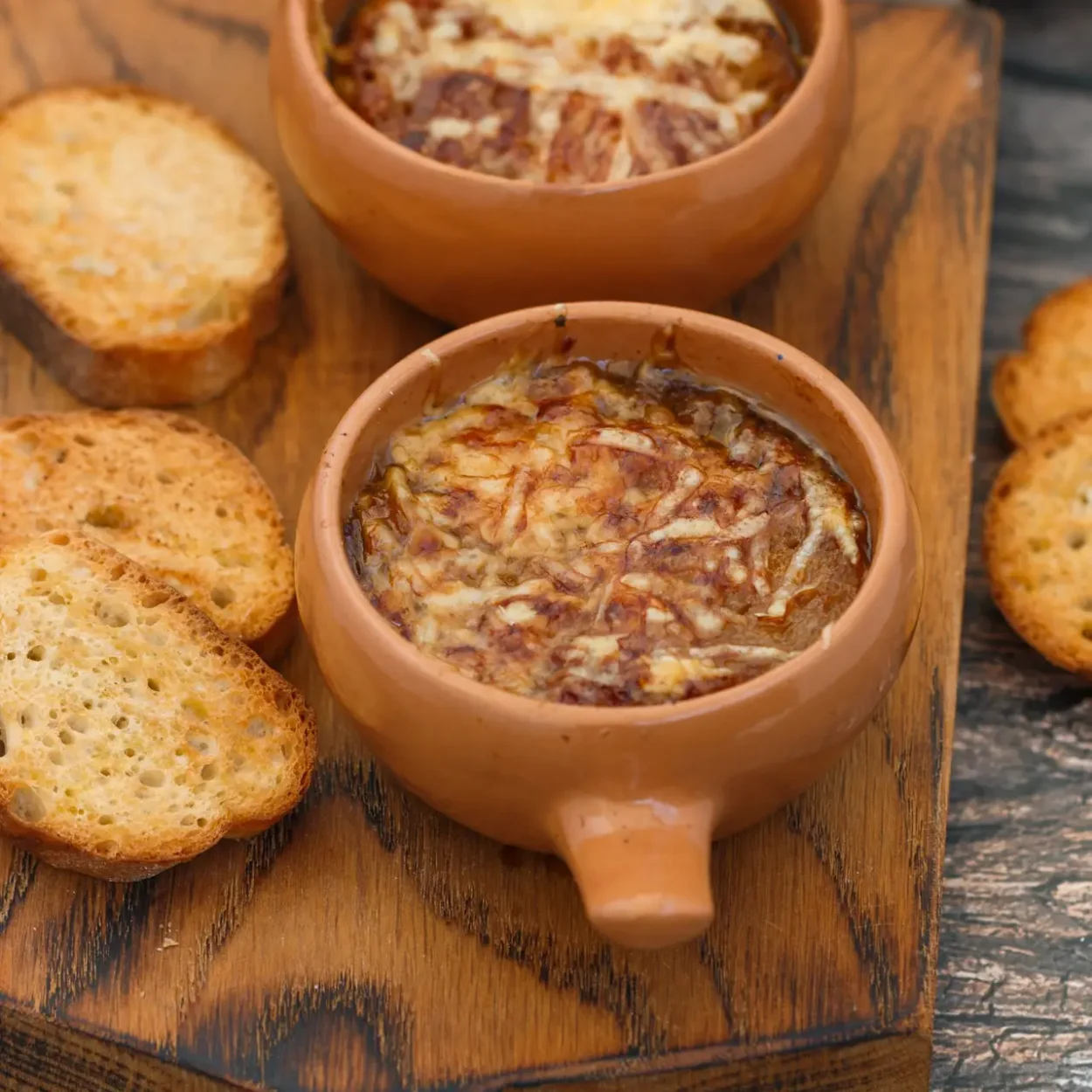 Two servings of traditional Italian onion soup with baguette and cheese